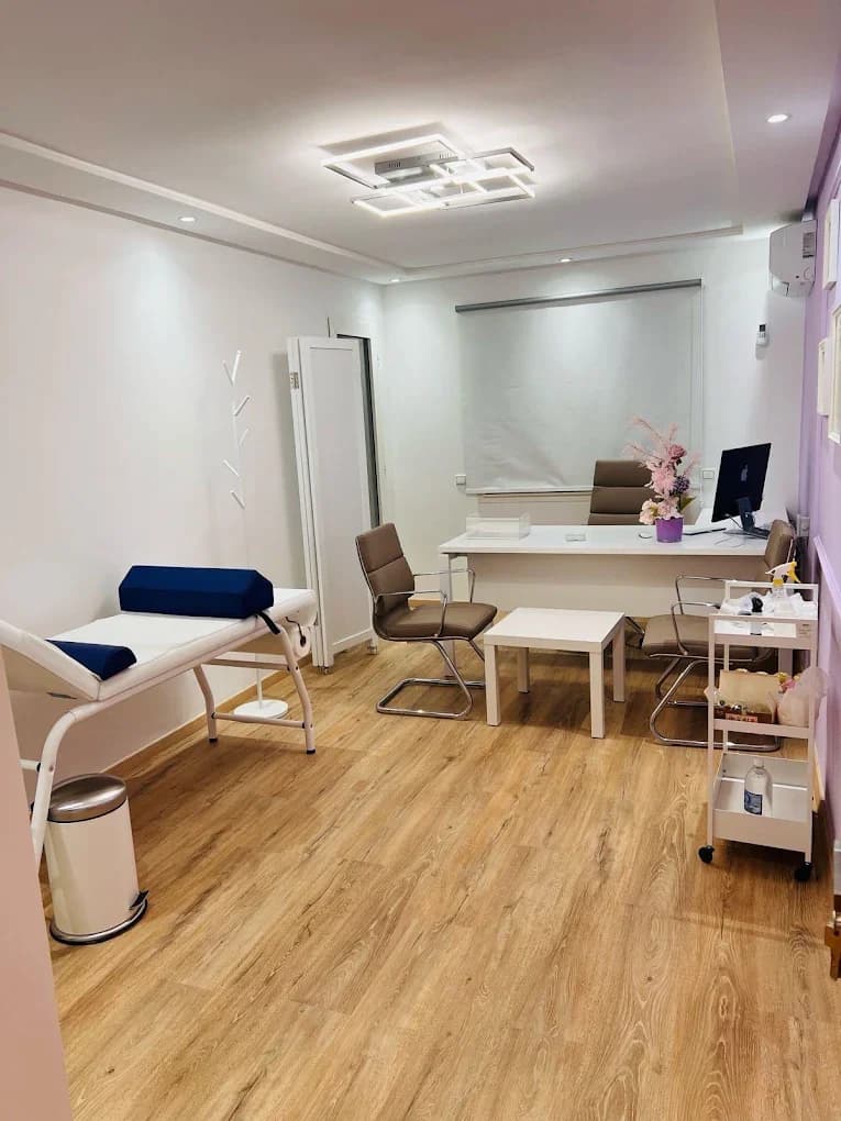 Bureau de consultation avec fauteuils, table d’examen et mur violet